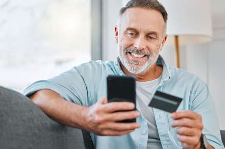 Foto: Mann mit Mobiltelefon und Kreditkarte